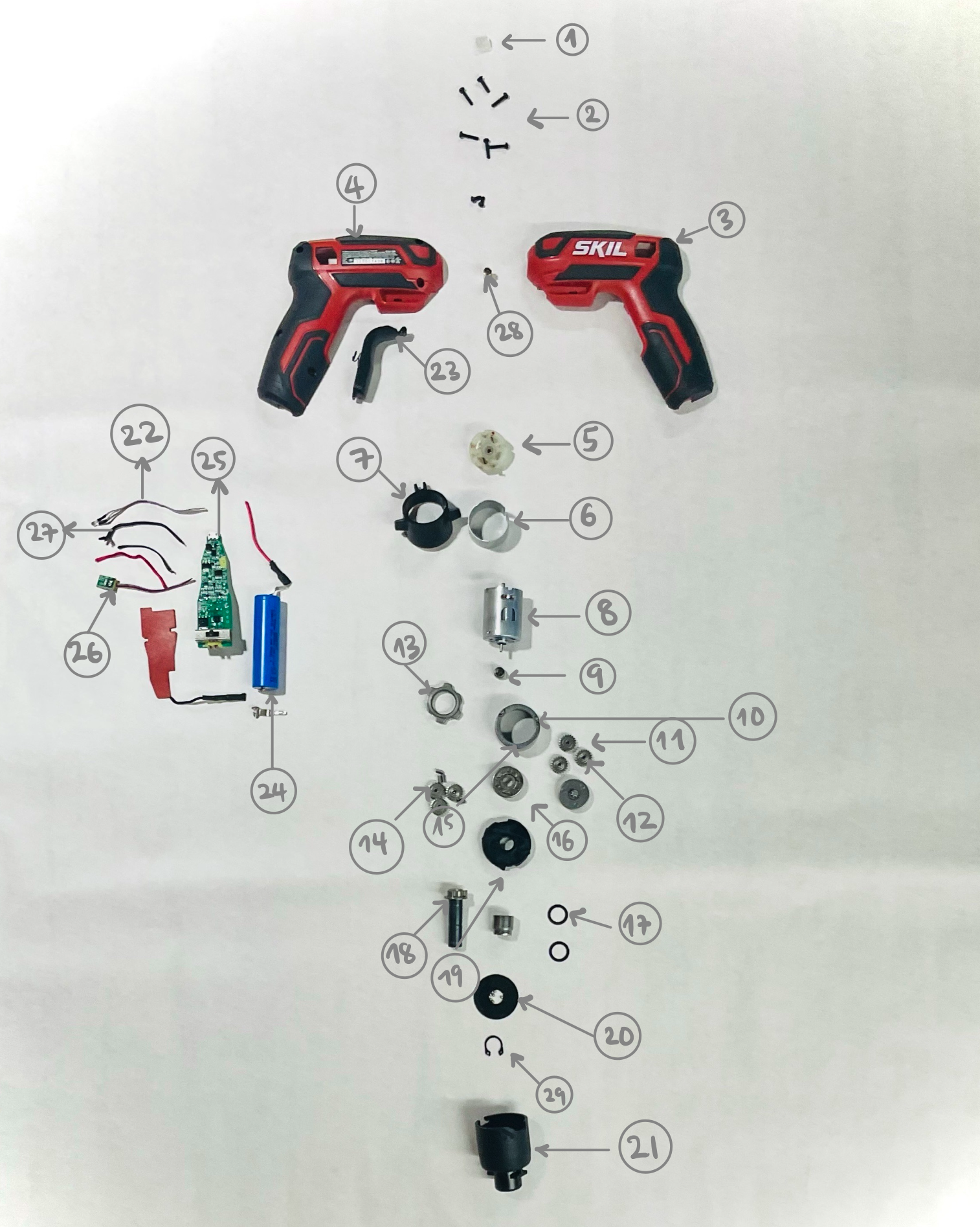Physical exploded view of the SKIL screwdriver with housing, electronics, motor, gears, battery, and hardware separated and labeled.